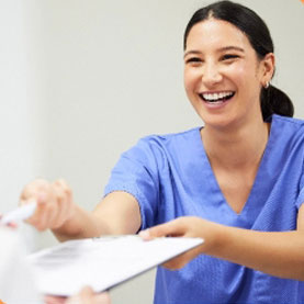 Compton Family Dental happy dental assistant handing a form to a patient